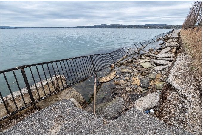 Waterfront view with mountains and damaged seawall infrastructure
