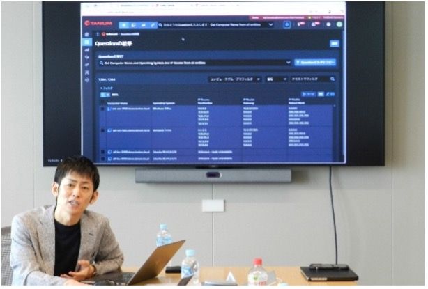 Man presenting Tanium Ask with dashboard displayed on screen