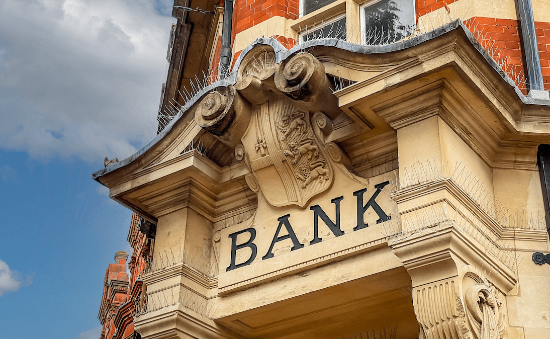 英国の銀行の石のファサード。装飾的なスクロールワークと「Bank」という言葉が入り口に刻まれています。