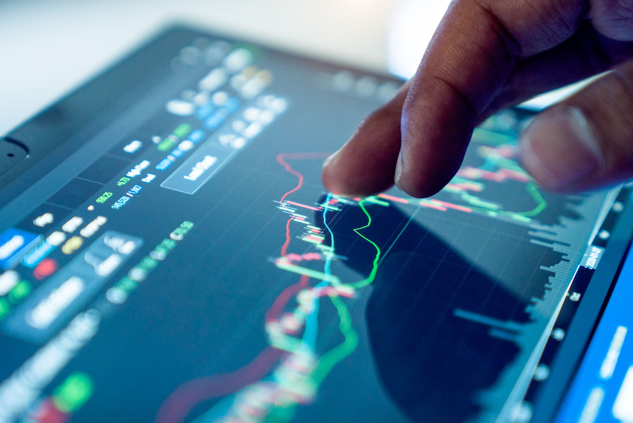 Market analysis: a finger points at financial charts on a touchscreen