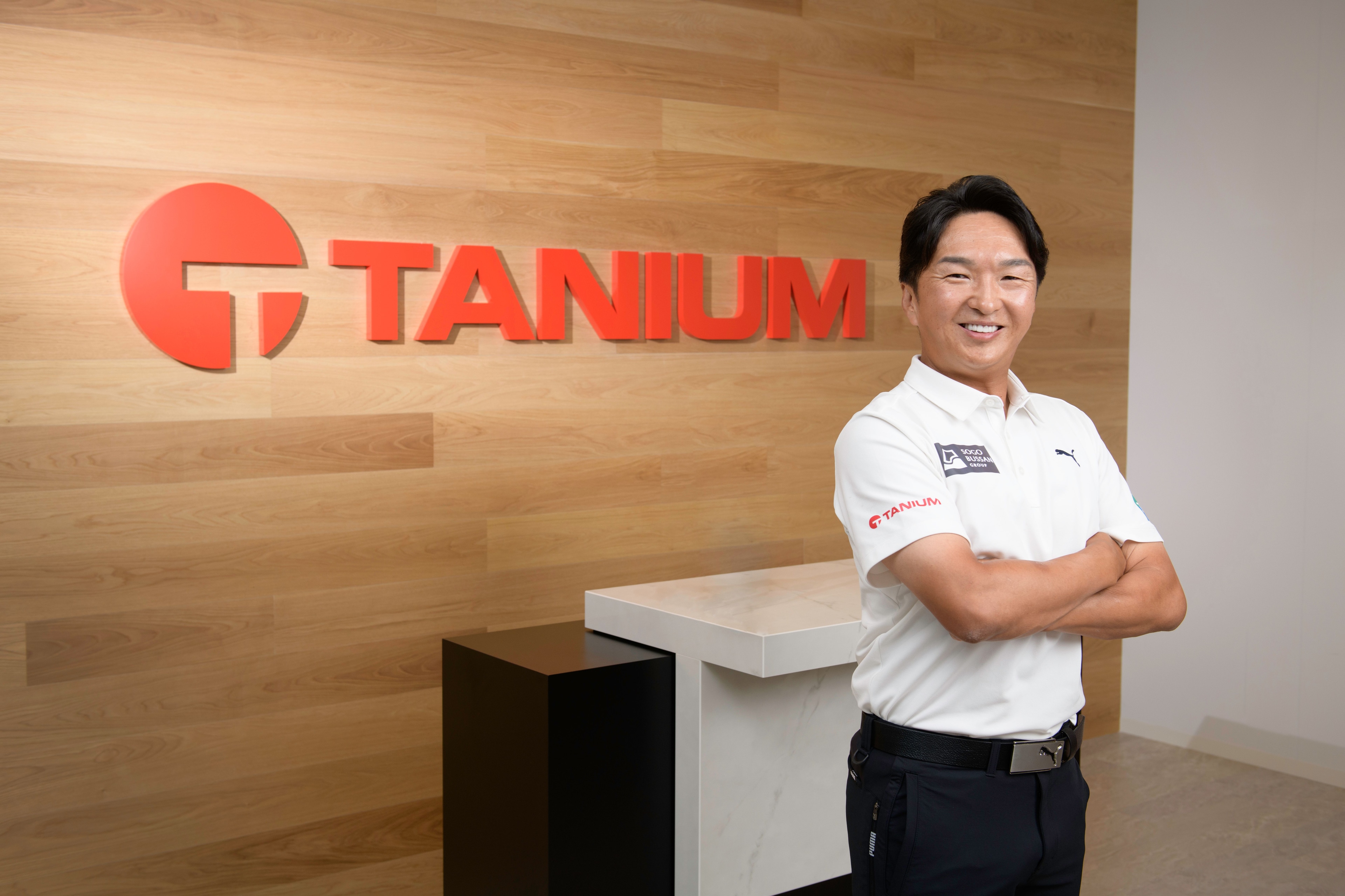Person standing in front of Tanium office logo wall
