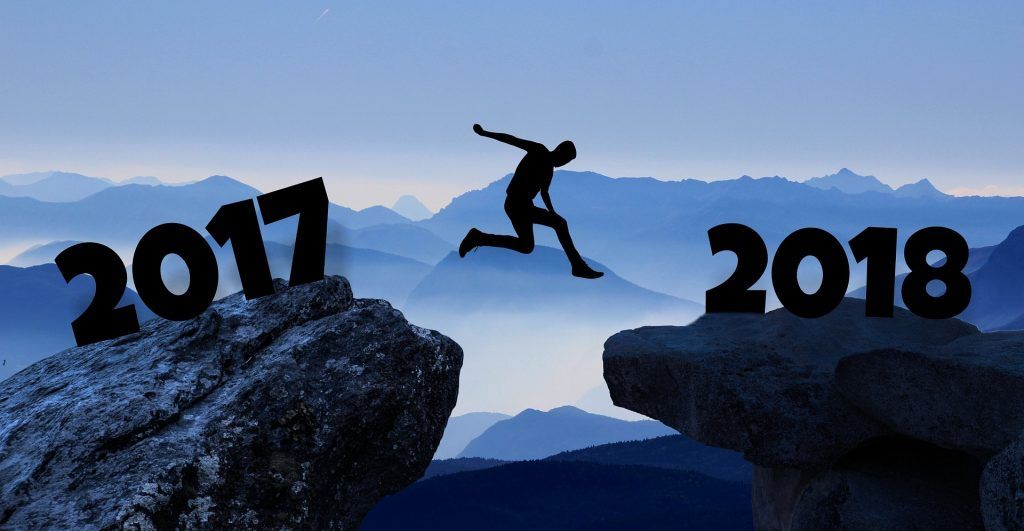 「 2017 」と「2018」と記された岩の間を飛び越える人のシルエット