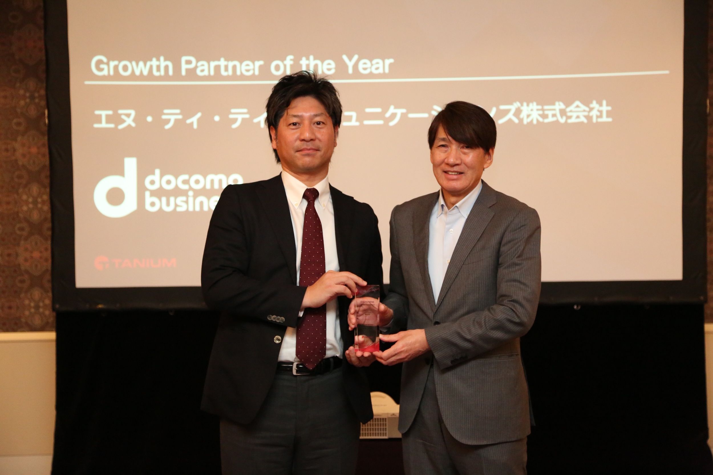Two men presenting award on stage with Growth Partner of the Year text displayed