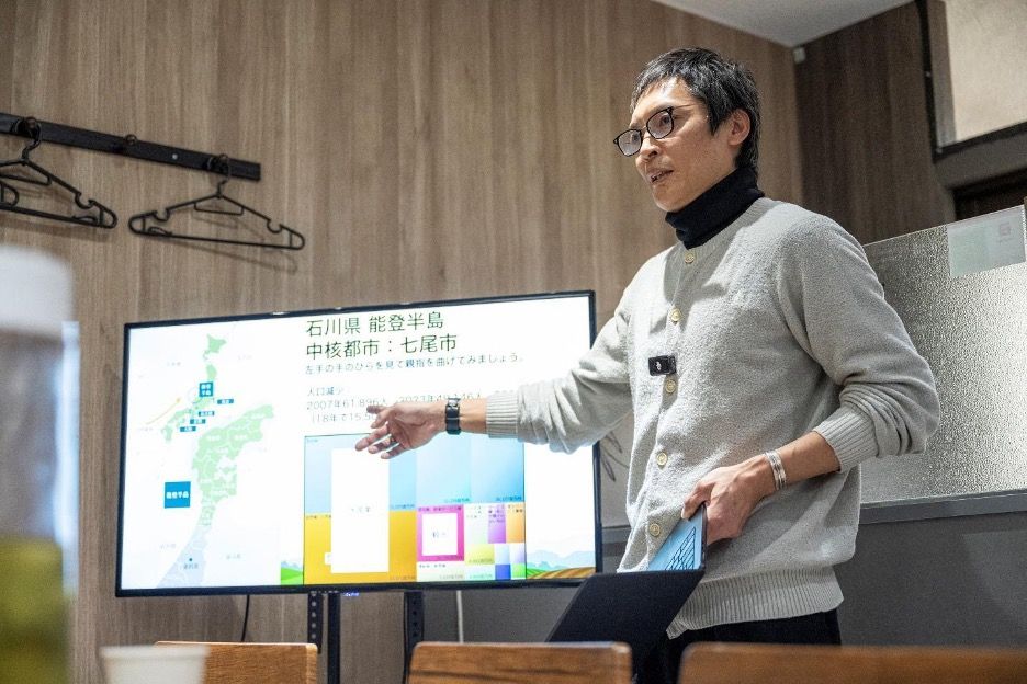 Photo of speaker presenting at event with Japan map and disaster relief data displayed