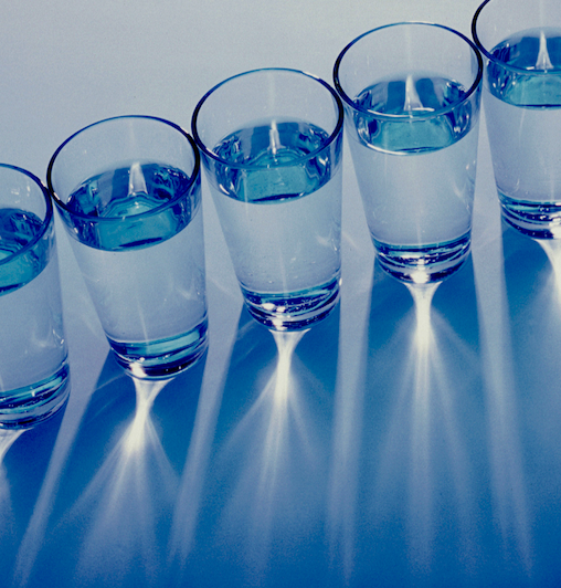 A photo of glasses of water in a diagonal row and seen from above.