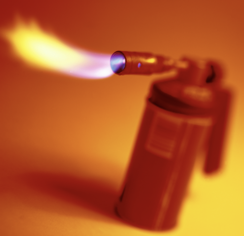 A photo of a red blowtorch spewing flames, and set against an orange backdrop.
