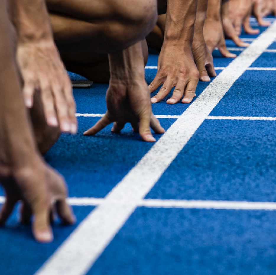 A closeup photo of runners' hands gripping the ground at the starting line of a race.